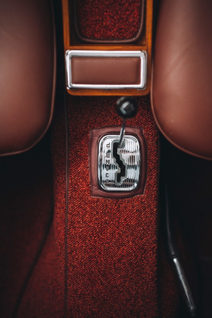 Detailaufnahme eines Oldtimer Schalthebels im Innenraum mit rotem Interieur